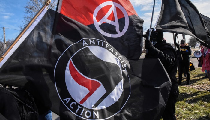 Members of the Great Lakes anti-fascist organization (Antifa) fly flags during a protest against the Alt-right outside a hotel in Warren, Michigan